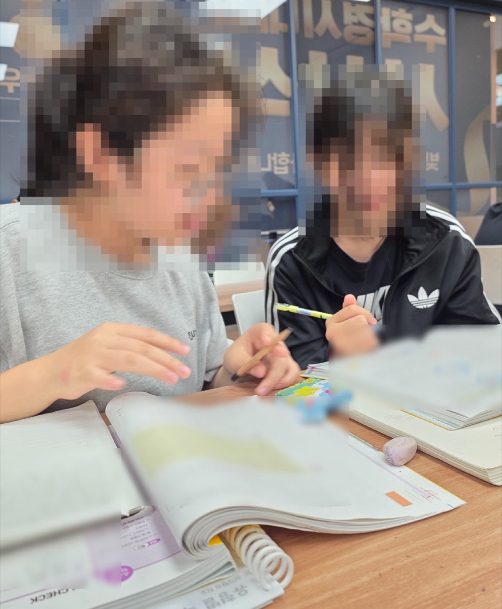 선생님과 학생이 수학 교재를 함께 보는 모습
