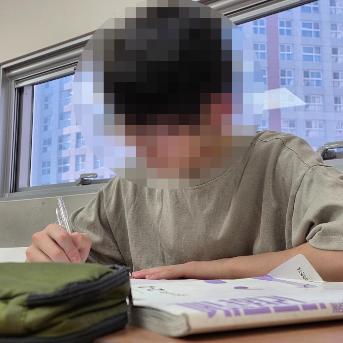 창가 자리에서 교재를 읽으며 문제를 푸는 학생